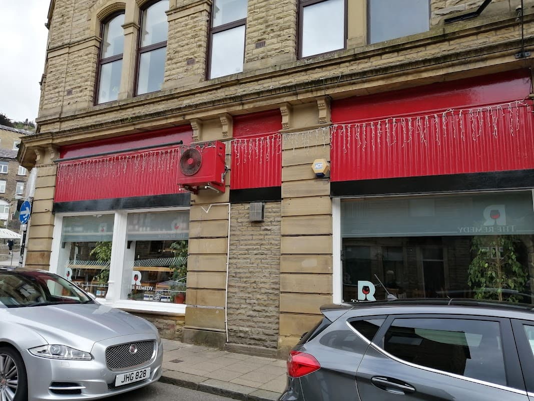 Red and stone façade of The Remedy Wine Merchants shop, featuring large windows and decorative elements.