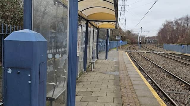 Shelter at a train station with "Arena Don Valley Stadium" sign, adjacent to railway tracks and paved platform.