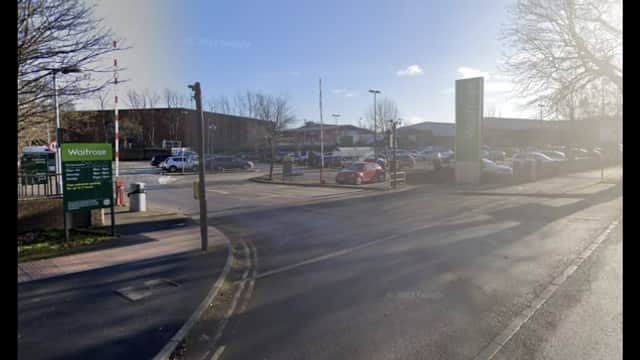 Car park entrance with signage for Waitrose, vehicles parked, and trees lining the area in York, Yorkshire.