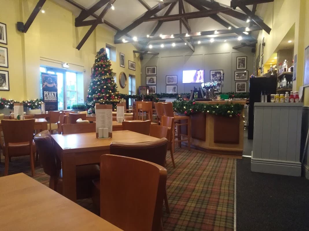 Cozy pub interior with wooden tables, festive decorations, a Christmas tree, and a bar area in Kirby Misperton.