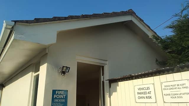 Exterior view of Dalesway Holiday Park featuring a fire point sign and notices about pets and vehicle parking.