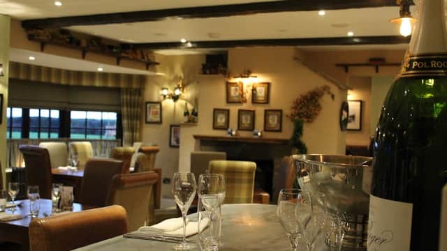 Cozy dining area with wooden beams, elegant table settings, and a champagne bucket in the foreground.