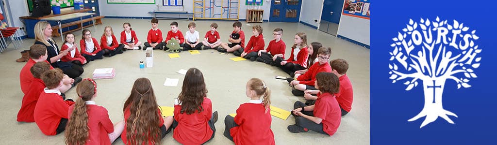 Students in red uniforms sitting in a circle on the floor, engaged in a group activity in a classroom setting.