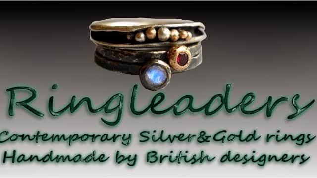 Contemporary silver and gold rings displayed in a gallery setting, featuring unique handmade designs.