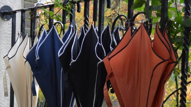 Colorful swimsuits hanging on a railing, with greenery in the background.
