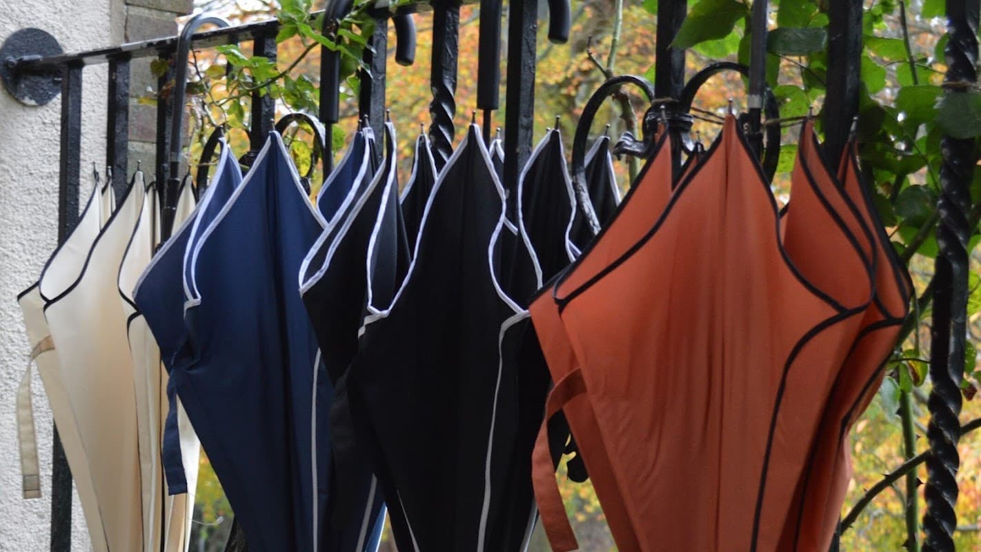 Colorful swimsuits hanging on a railing, with greenery in the background.