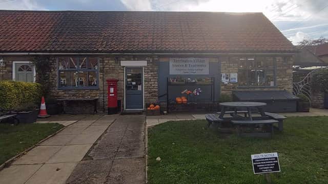 Quaint stone building with a red post box, outdoor seating, pumpkins, and a sign for Terrington Village Store.