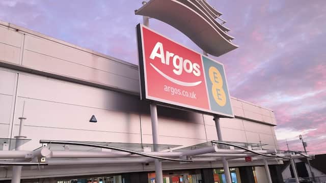 Argos storefront with large sign, featuring a pink and blue sky in the background at dusk.