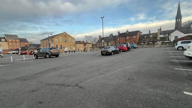 Chapel Street car park in Knaresborough, featuring several parked cars and historic buildings under a cloudy sky.