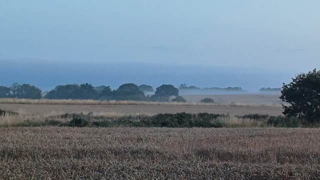 Mist-covered fields with distant trees under a soft blue sky at dawn in Havercroft, Yorkshire.