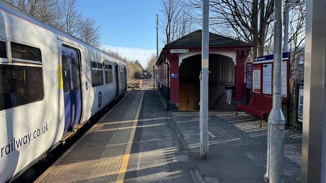 Lockwood Station platform with a train, benches, a ticket booth, and trees lining the background in South Crosland, Yorkshire.