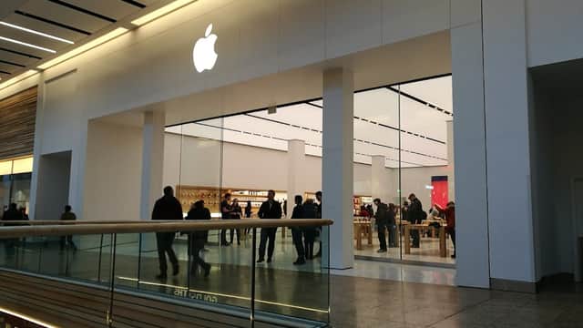 Apple store entrance in Meadowhall, featuring a large logo and a modern, spacious interior with customers browsing.