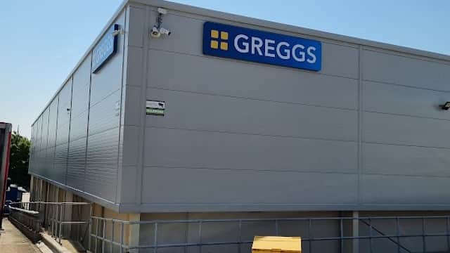 Greggs bakery building with a blue sign, clear sky, and a yellow bin nearby in Leeds, Yorkshire.