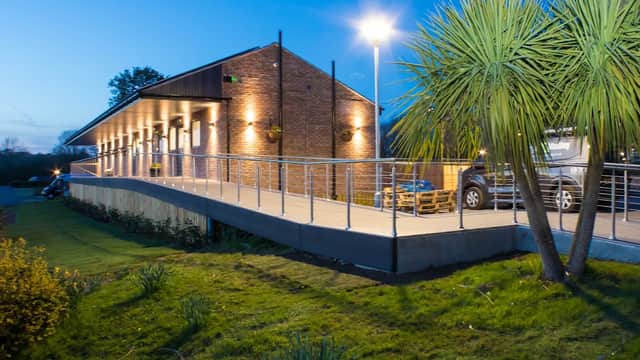 Modern building with warm lights, surrounded by greenery and palm-like plants, at dusk in York Naburn Lock Caravan Park.
