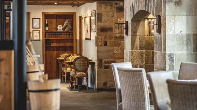 Cozy dining area with stone walls, wooden beams, and rustic furniture at The Saddle Room Restaurant in Coverham.