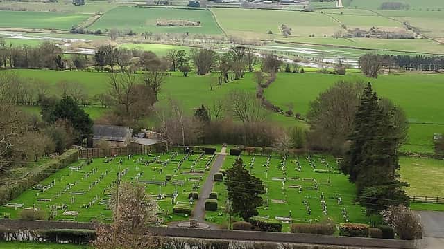 Aerial view of a cemetery surrounded by lush green fields and rolling hills in Leyburn, Yorkshire.