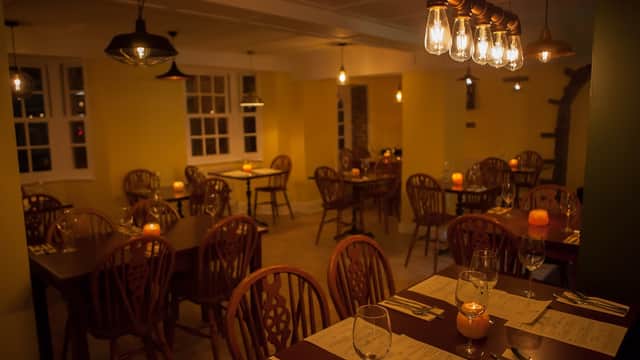 Cozy dining area with wooden tables, chairs, and warm lighting, creating an inviting atmosphere at Racha Thai Bistro.