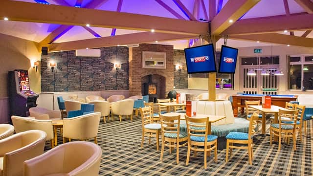 Cozy restaurant interior with wooden beams, seating areas, TVs, and a fireplace in Lebberston, Yorkshire.