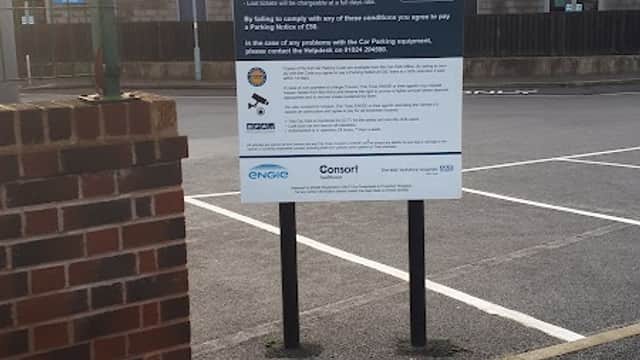 Welcome sign for Pontefract Hospital Visitors Car Park with parking rules and information, surrounded by empty parking spaces.