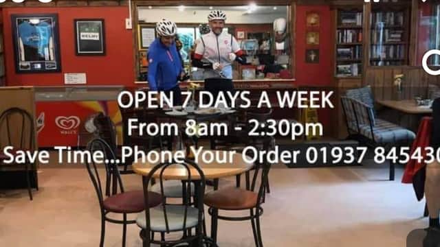 Interior of The Great British Diner with customers, cyclists, and a sign displaying opening hours and contact info.