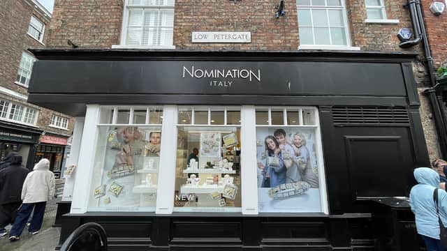 Jewellery store "Nomination Italy" with large windows displaying products, located on a cobblestone street.