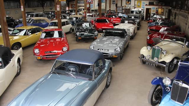 Classic car showroom featuring a variety of vintage and sports cars in a spacious, well-lit environment.