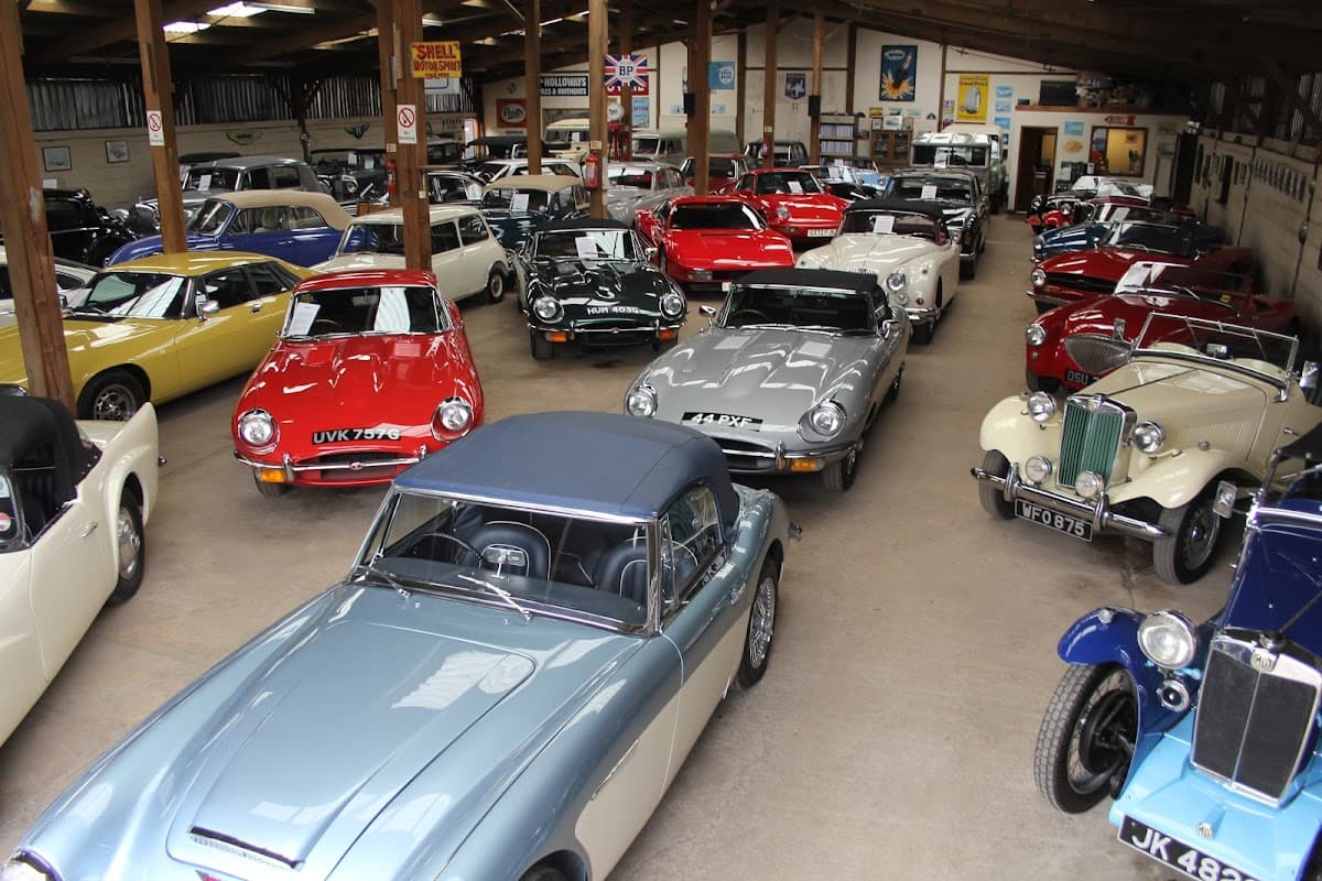 Classic car showroom featuring a variety of vintage and sports cars in a spacious, well-lit environment.