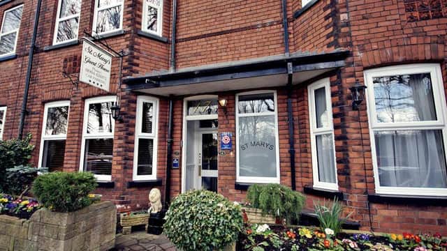 Brick facade of St Mary's Guest House in York, featuring a welcoming entrance and colorful flower beds.