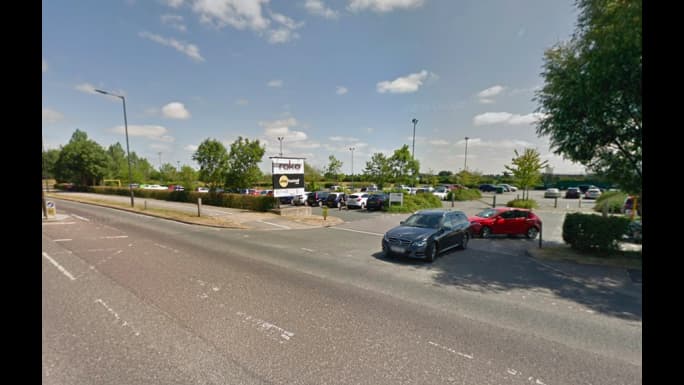 Pay & Display parking area in Earswick, Yorkshire, with multiple cars and greenery under a clear blue sky.