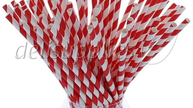 A glass vase filled with red and white striped drinking straws.