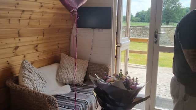 Cozy interior of a cabin featuring a balloon, flowers, and a view of the outdoors through large glass doors.