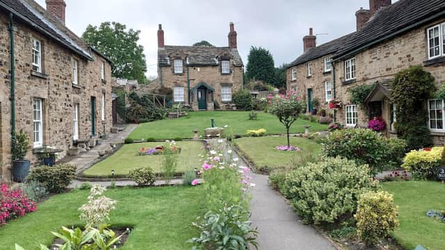 Quaint village scene with stone cottages, manicured gardens, and colorful flowers in Wentworth, Yorkshire.