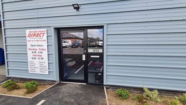 Entrance to Motor Parts Direct with an "OPEN" sign and operating hours displayed on the wall.