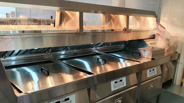 Stainless steel fish and chip fryer station with multiple fryers and a clean, organized workspace.