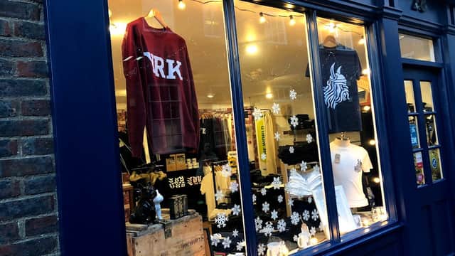Clothing shop window featuring sweatshirts, t-shirts, and decorative items with lights and snowflake accents.