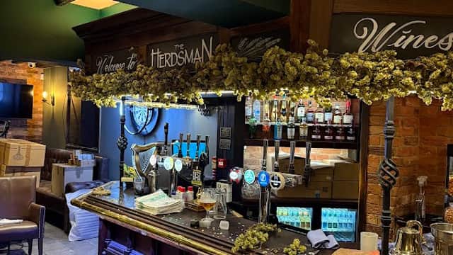Welcoming bar area with wooden counter, beer taps, and decorative hops, set in a cozy pub atmosphere.