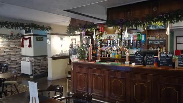 Cozy restaurant interior with a wooden bar, festive decorations, and tables set for dining.