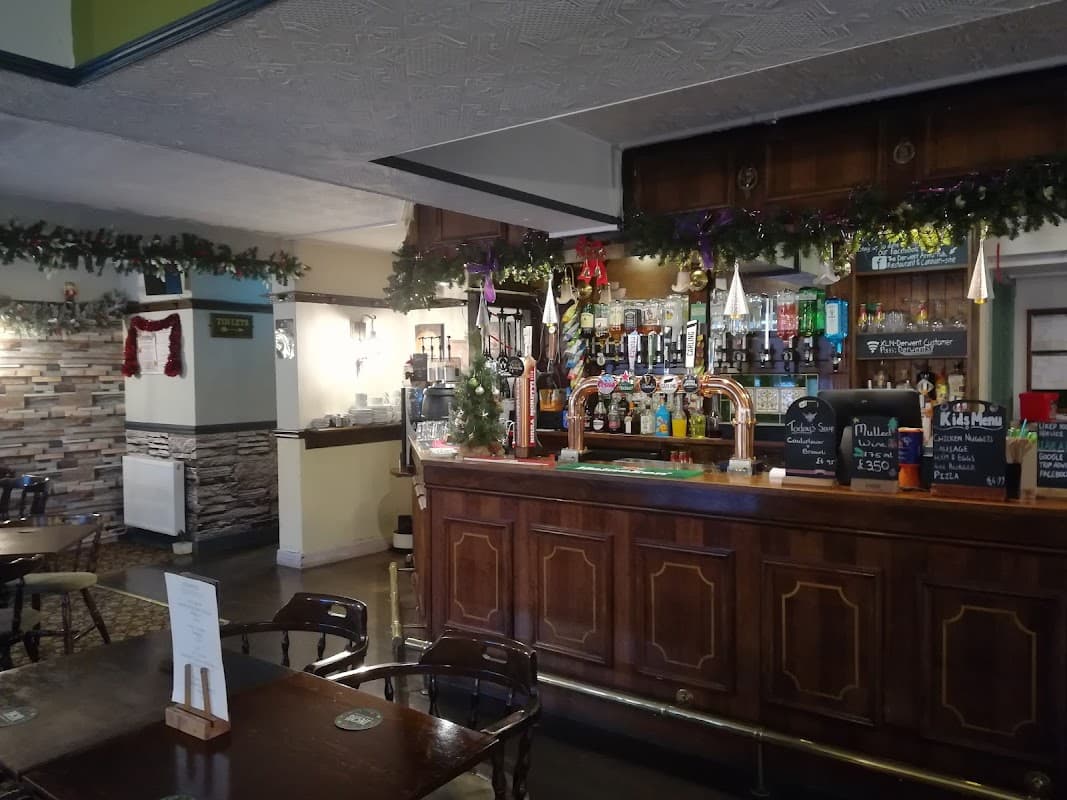 Cozy restaurant interior with a wooden bar, festive decorations, and tables set for dining.