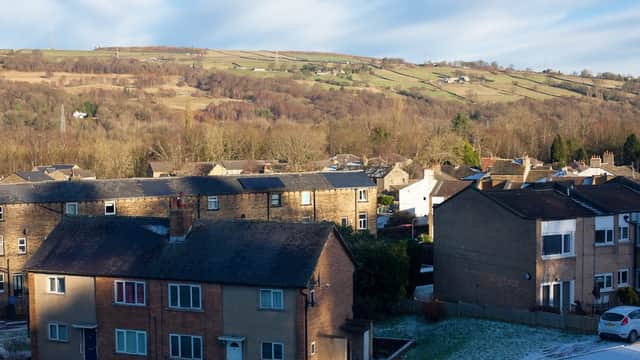 Dalesgate Hotel surrounded by residential buildings and rolling hills under a partly cloudy sky in Utley, Yorkshire.