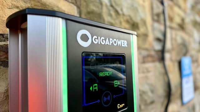 Giga Power Charging Station with illuminated display showing "READY" and options A and B, set against a stone wall.
