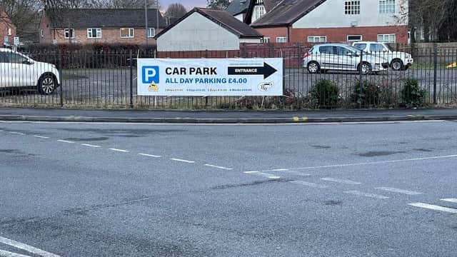 Bevan Grove Car Park sign displaying £4 all-day parking, with nearby residential buildings and parked cars.