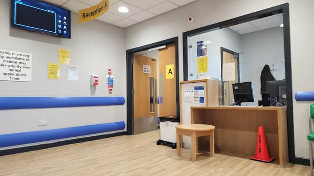Reception area of Rotherham Community Health Centre with wooden desk, seating, and informational signage.