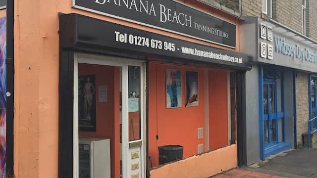 Banana Beach Tanning Studio storefront with orange facade, large sign, and nearby shops in Wibsey, Yorkshire.