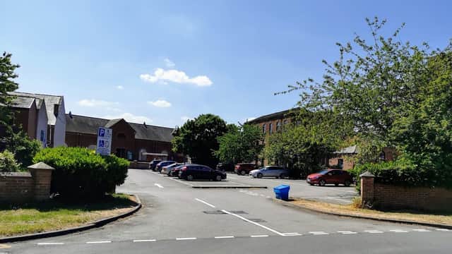Free parking area with several cars, trees, and a blue bin under a clear blue sky in Tingley, Yorkshire.