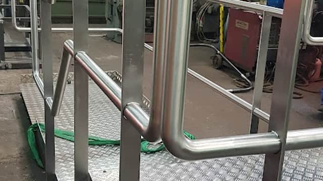 Metal railing on a raised platform with a textured surface, surrounded by industrial equipment in a workshop.