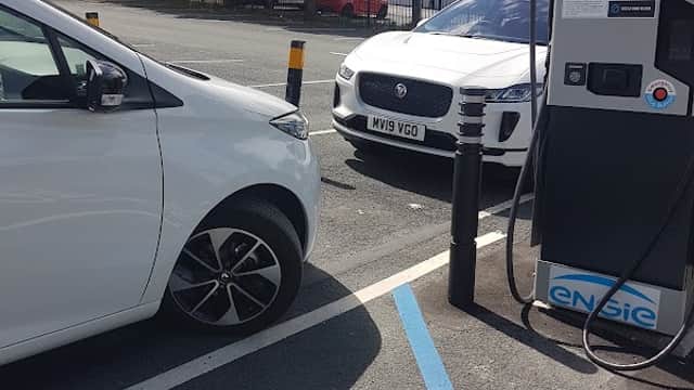 Pay & Display car park with two parked cars, one white and one silver, near charging station in Pontefract, Yorkshire.