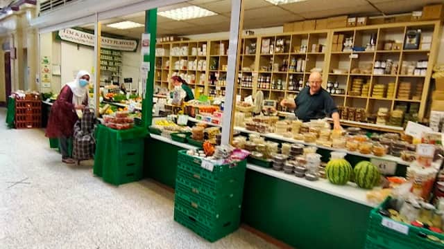 Vibrant market stall named "Tasty Flavours" displaying fresh produce and various goods in Doncaster Market.