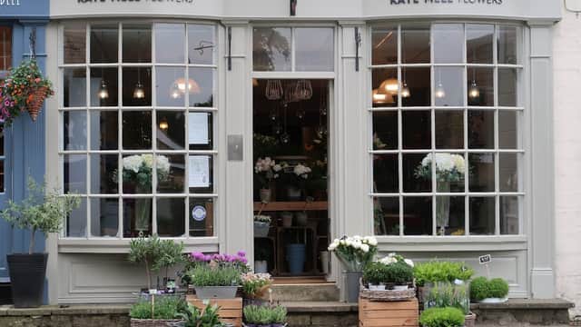 Charming flower shop with large windows, planters of flowers, and greenery outside, located in Boston Spa, Yorkshire.