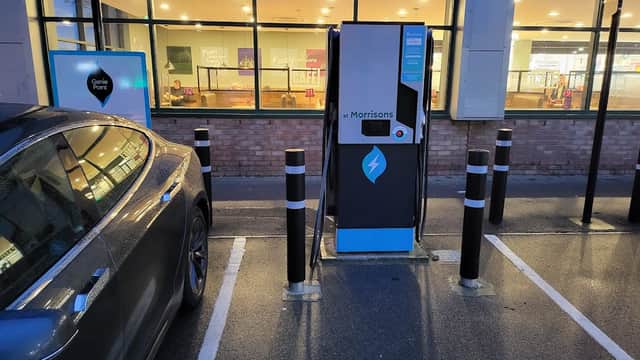 GeniePoint electric vehicle charging station next to a parked car, with a café visible in the background.
