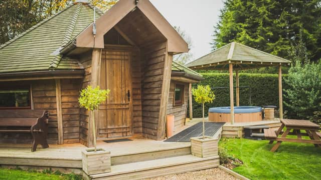 Cozy wooden lodge with a sloped roof, hot tub, picnic area, and lush greenery in Brandesburton, Yorkshire.